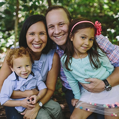 Dr. Jeff S. Dillingham hugging his wife and two children while smiling in a park